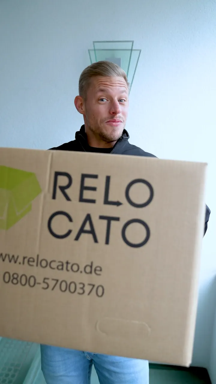 Szene aus dem Relocato-Imagefilm: Mitarbeiter trägt einen Relocato-Umzugskarton