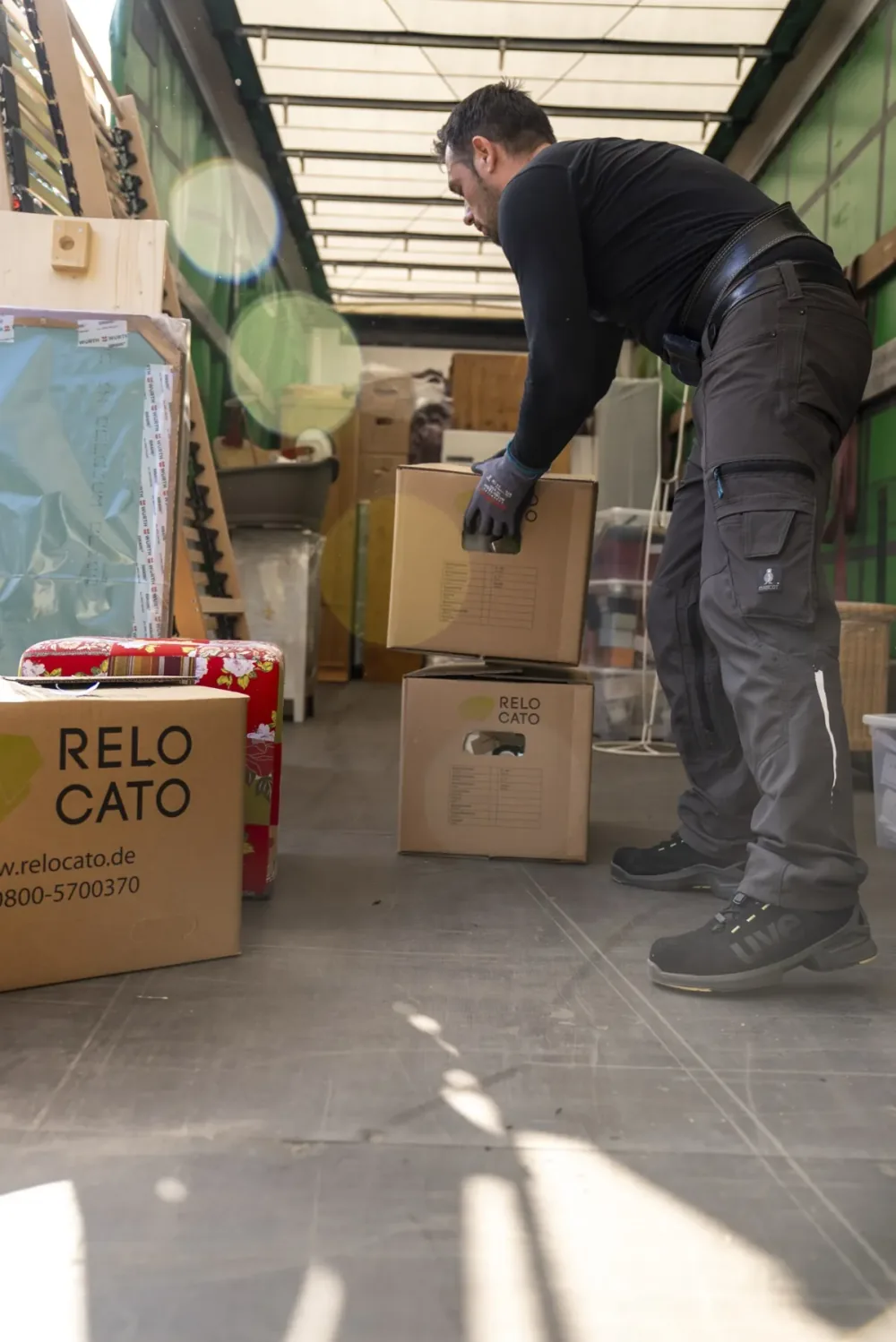 Relocato-Mitarbeiter hebt beschriftete Umzugskartons im Laderaum