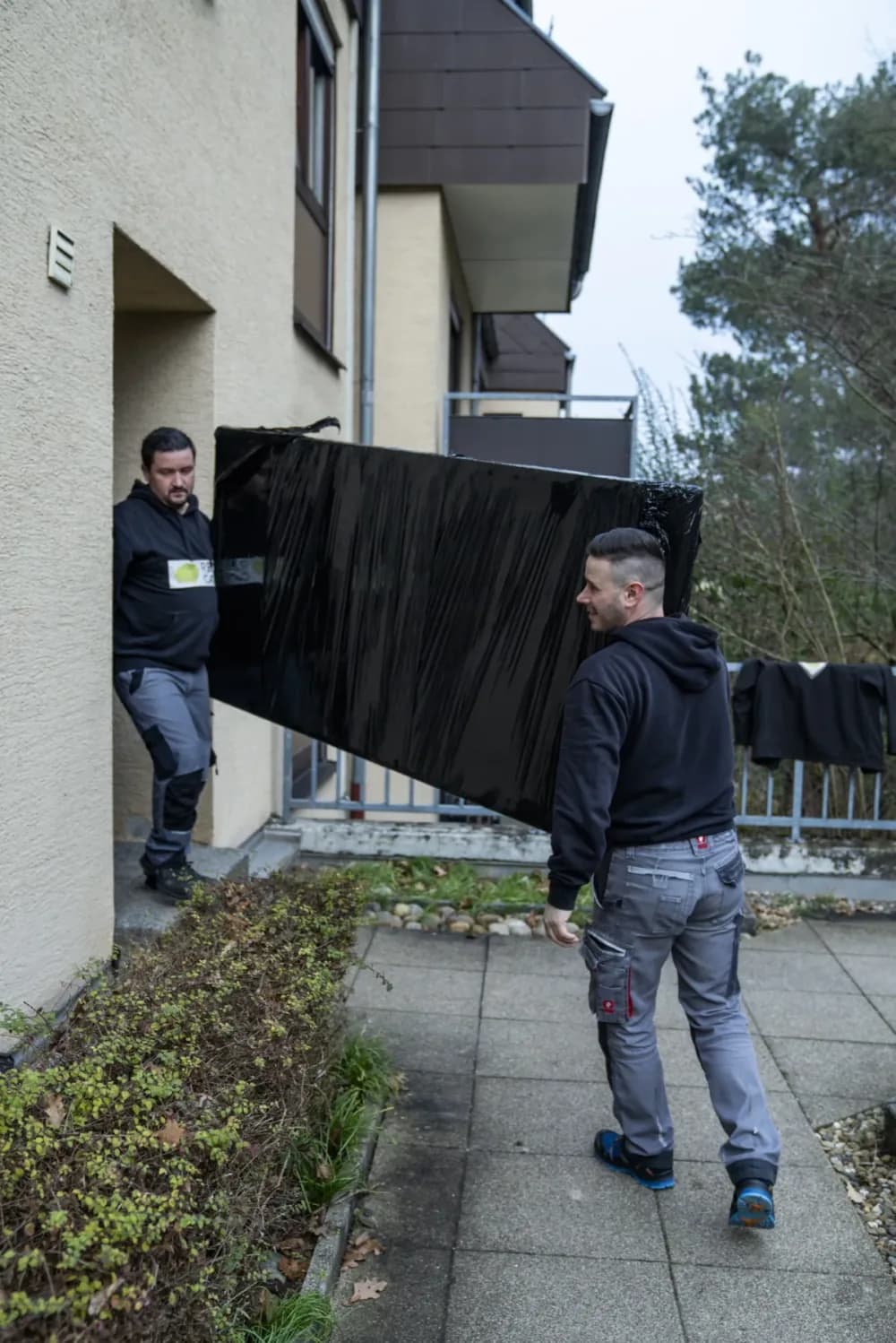 Zwei Relocato-Mitarbeiter tragen einen verpackten Fernseher aus dem Haus